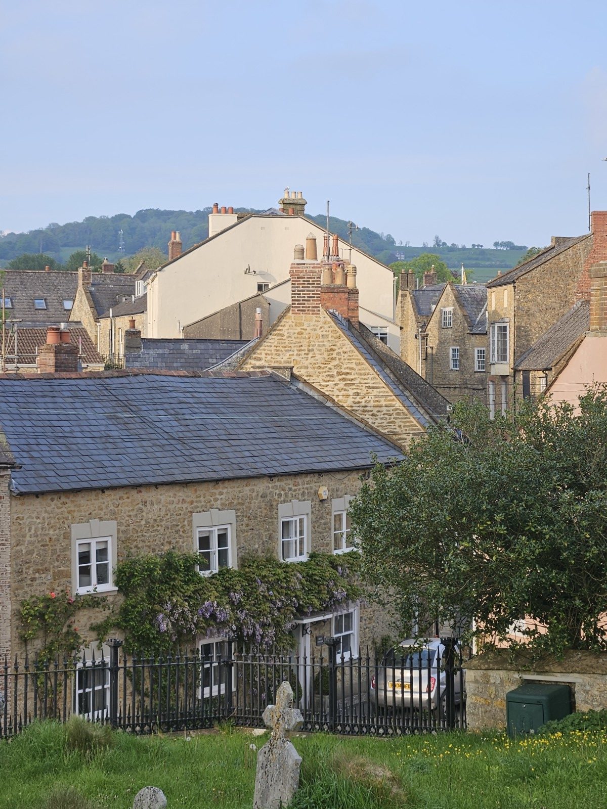 Hamstone houses and slate roofs in Beaminster seen from the churchyard, with the Dorset hills beyond